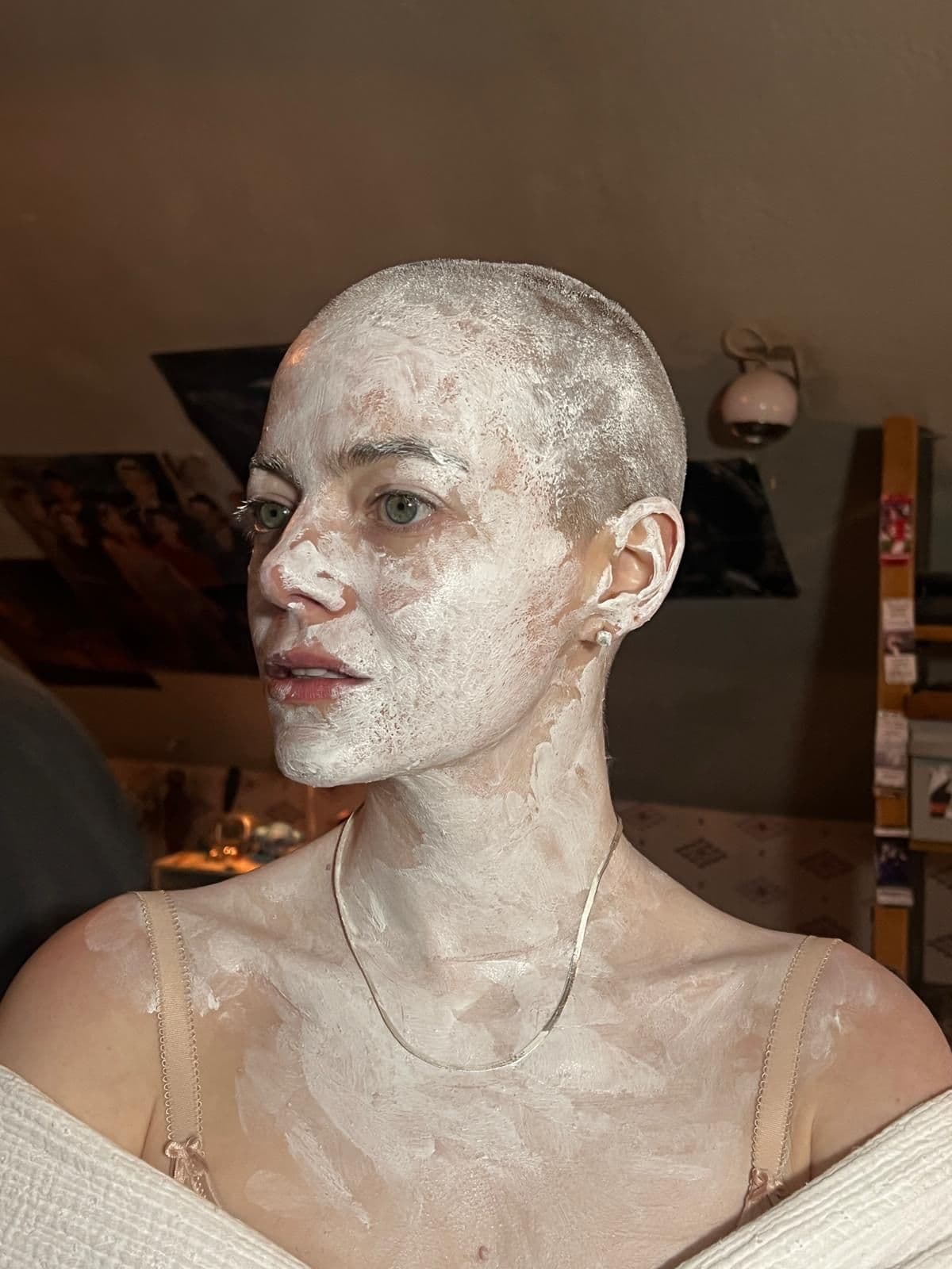 An iPhone photo of actress Emma Stone with a shaved head and covered in white paint, on set of the movie "Bugonia." 