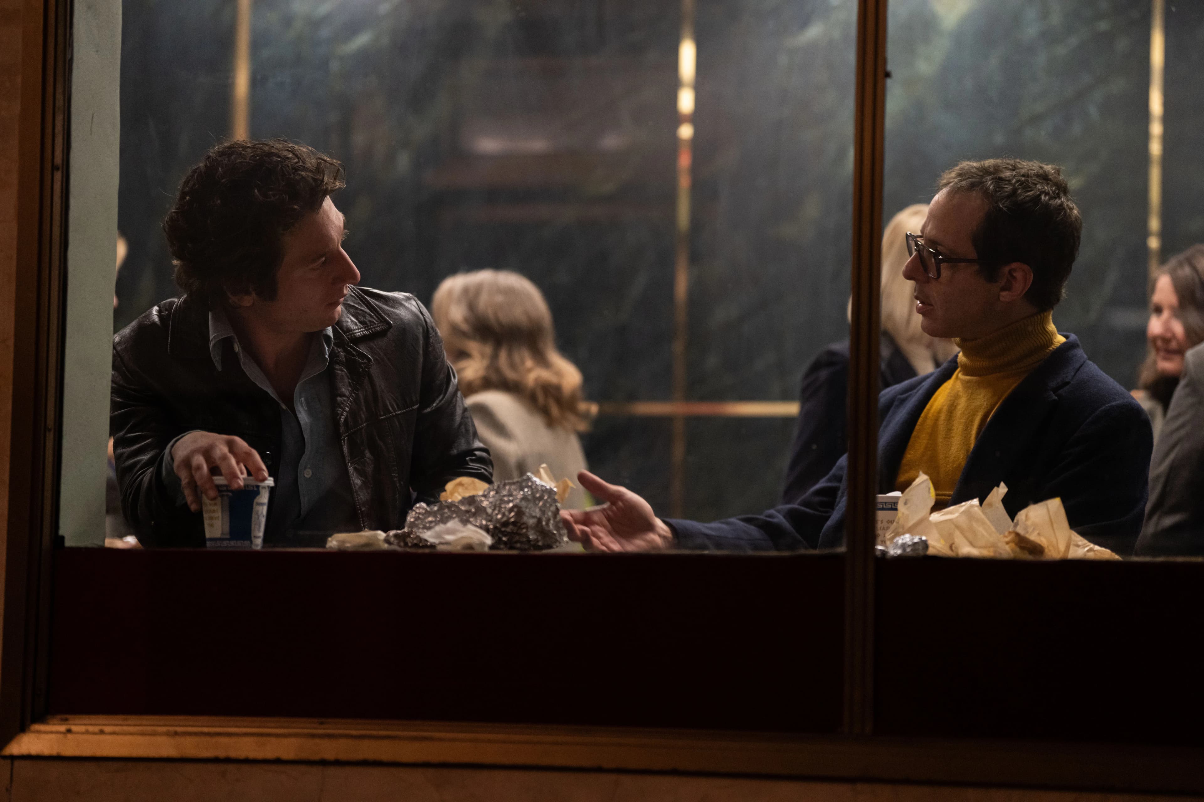 Actors Jeremy Allen White and Jeremy Strong sit at a diner and chat in a still from "Deliver Me From Nowhere." 