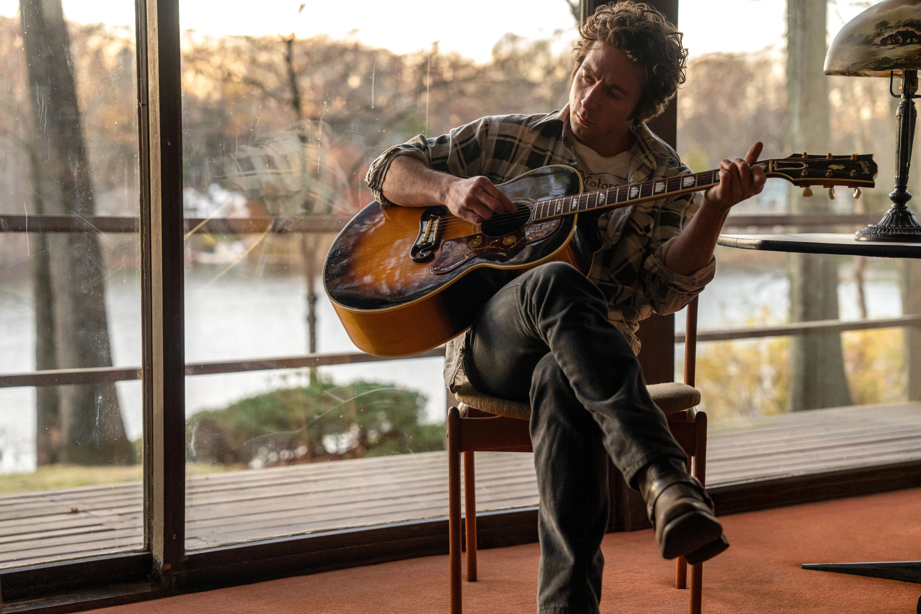 Actor Jeremy Allen White as Bruce Springsteen, playing a guitar in a still from "Deliver Me From Nowhere." 