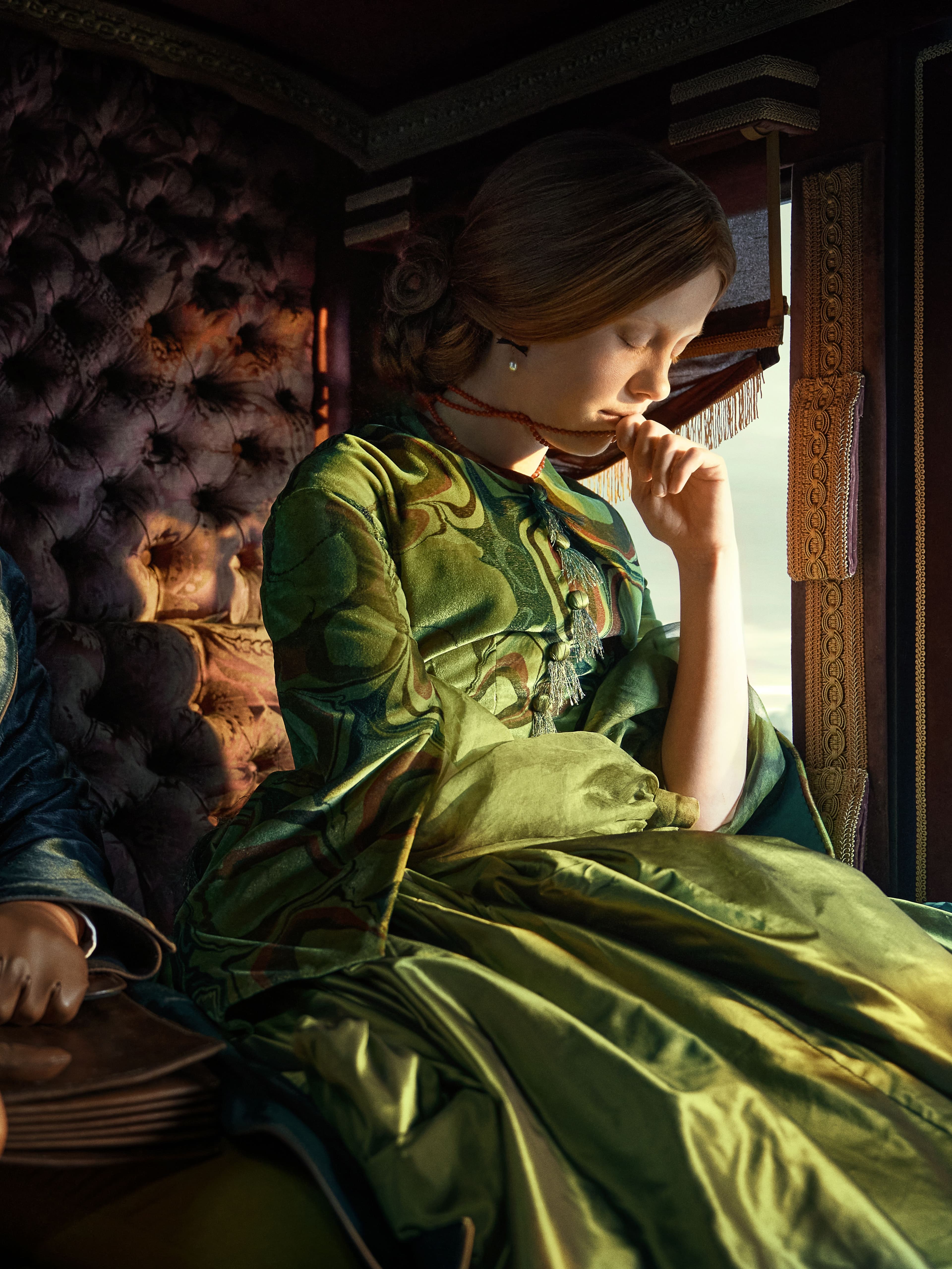Actors Felix Kammerer and Mia Goth sit in the back of a sunny horse-drawn carriage in a still from Frankenstein. 
