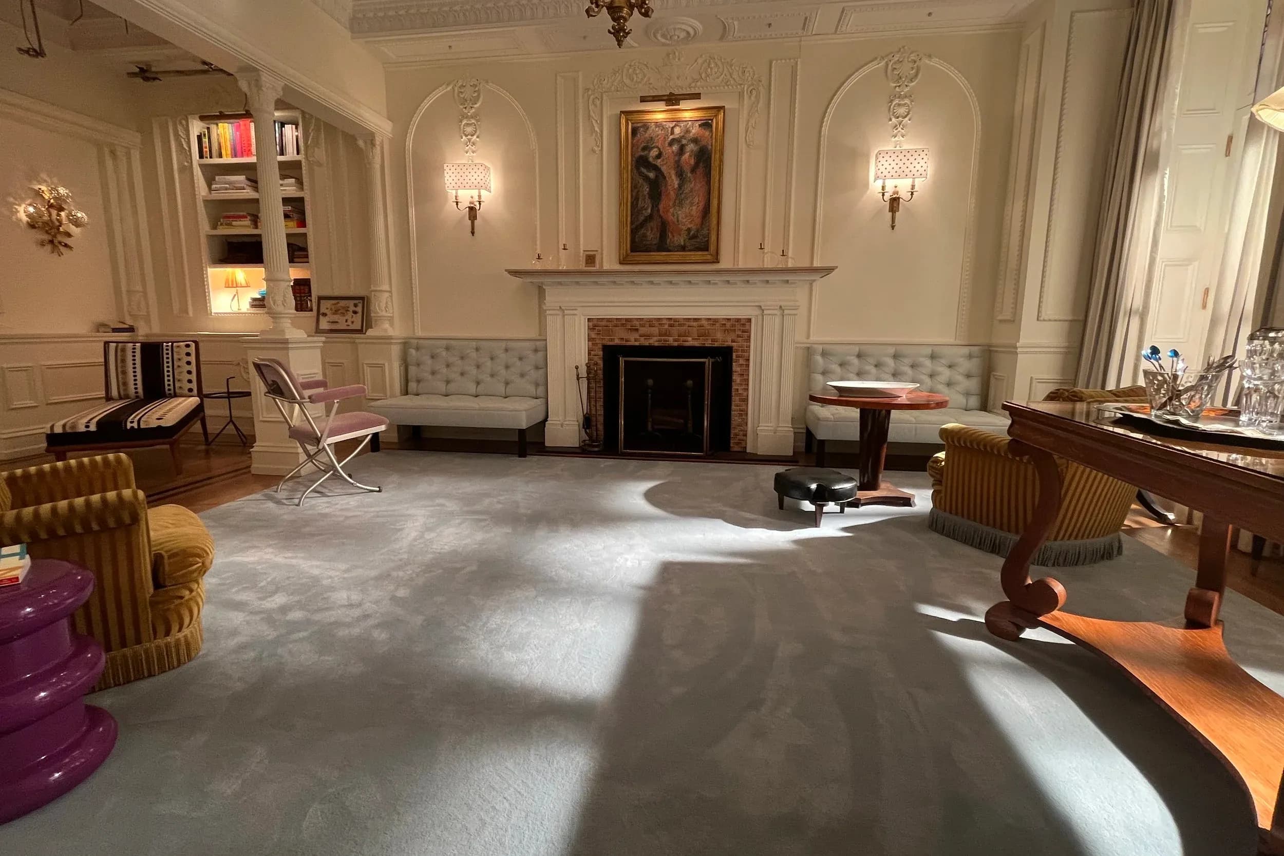 A large sitting room with light gray rug, chandelier, and fireplace, from HBO series "And Just Like That." 