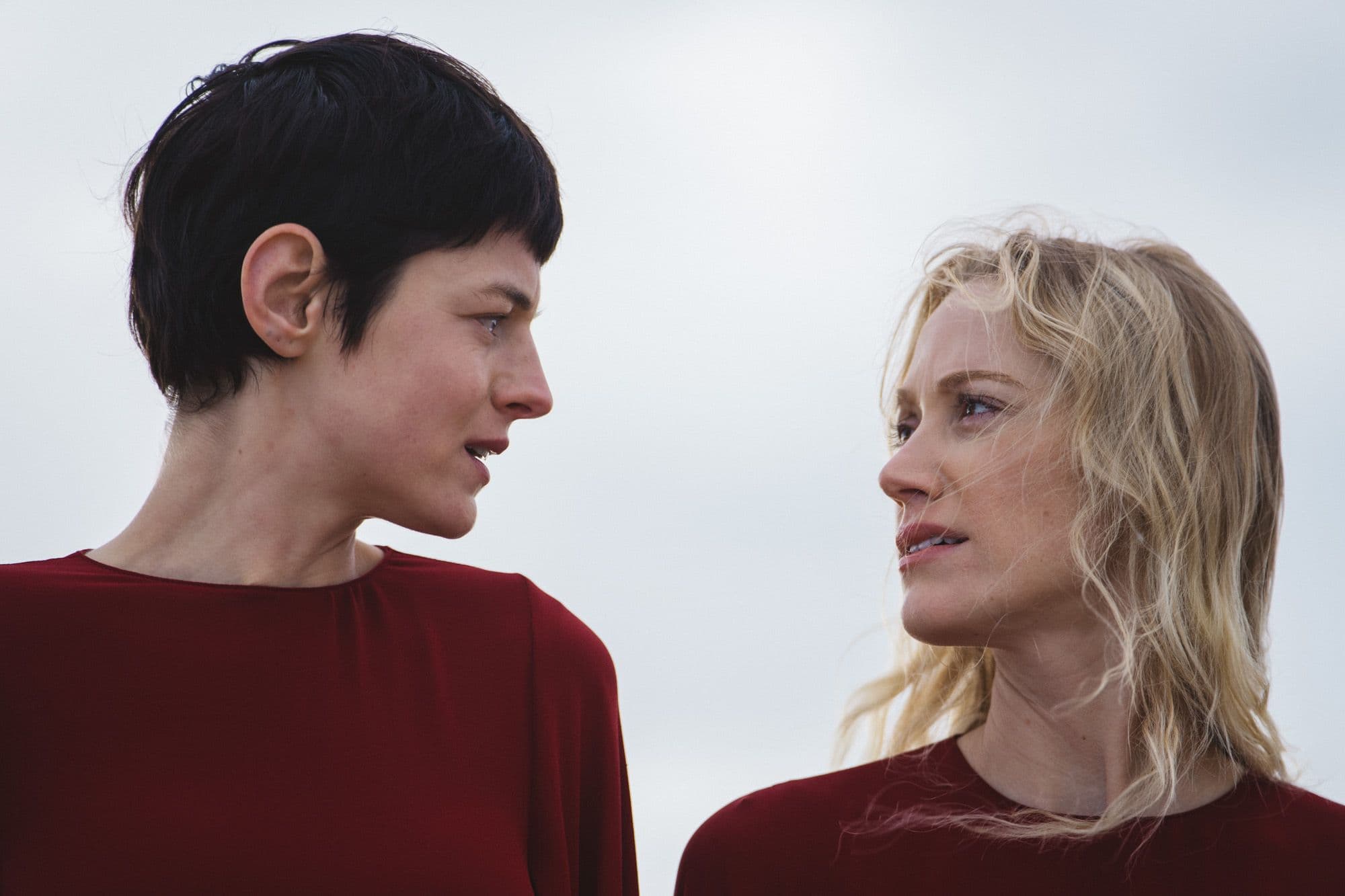 Close up of Emma Corrin and Maika Monroe looking at each other outside in "100 Nights of Hero."