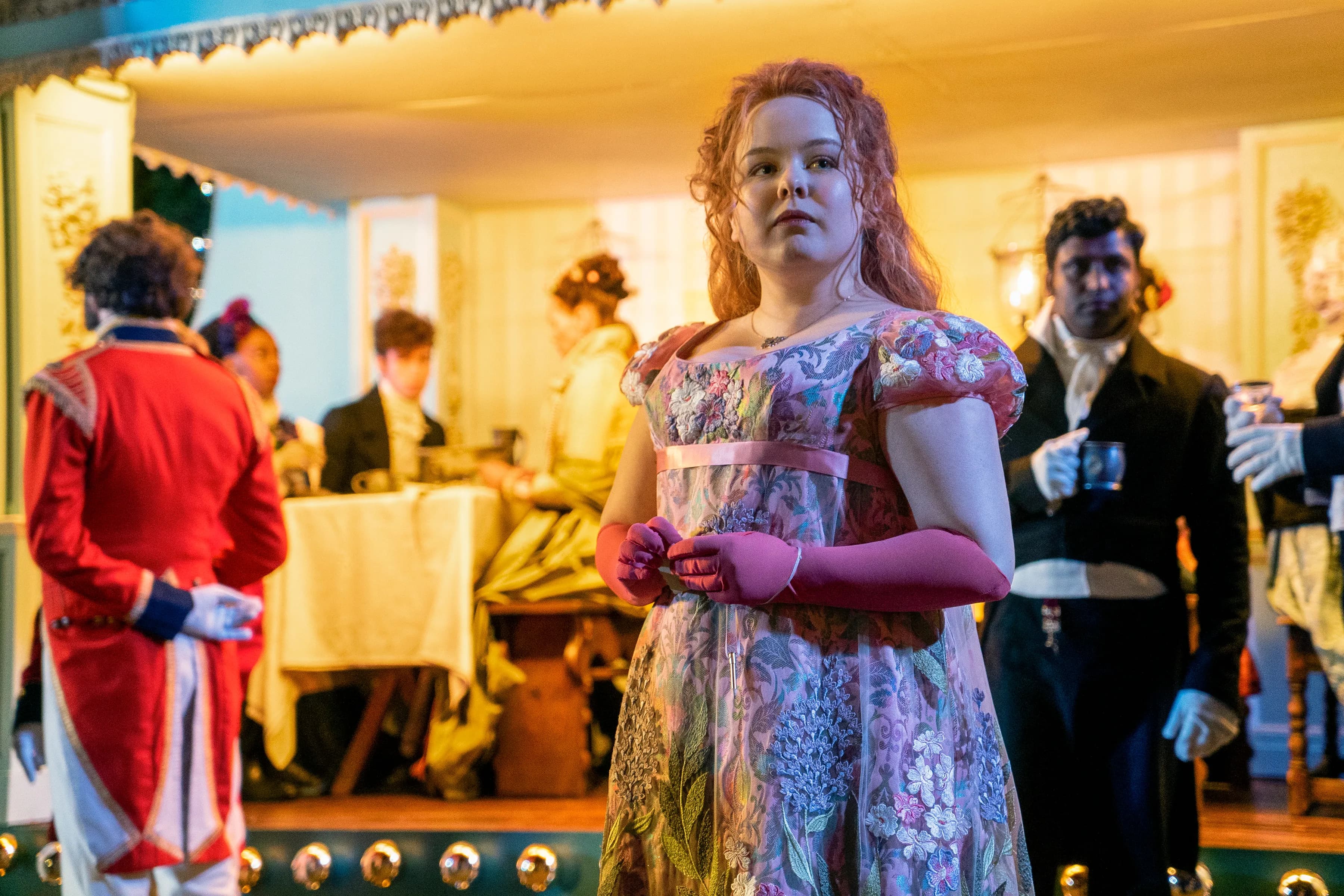 Actress Nicola Coughlin on set of Bridgerton in a pink dress and pink opera gloves.