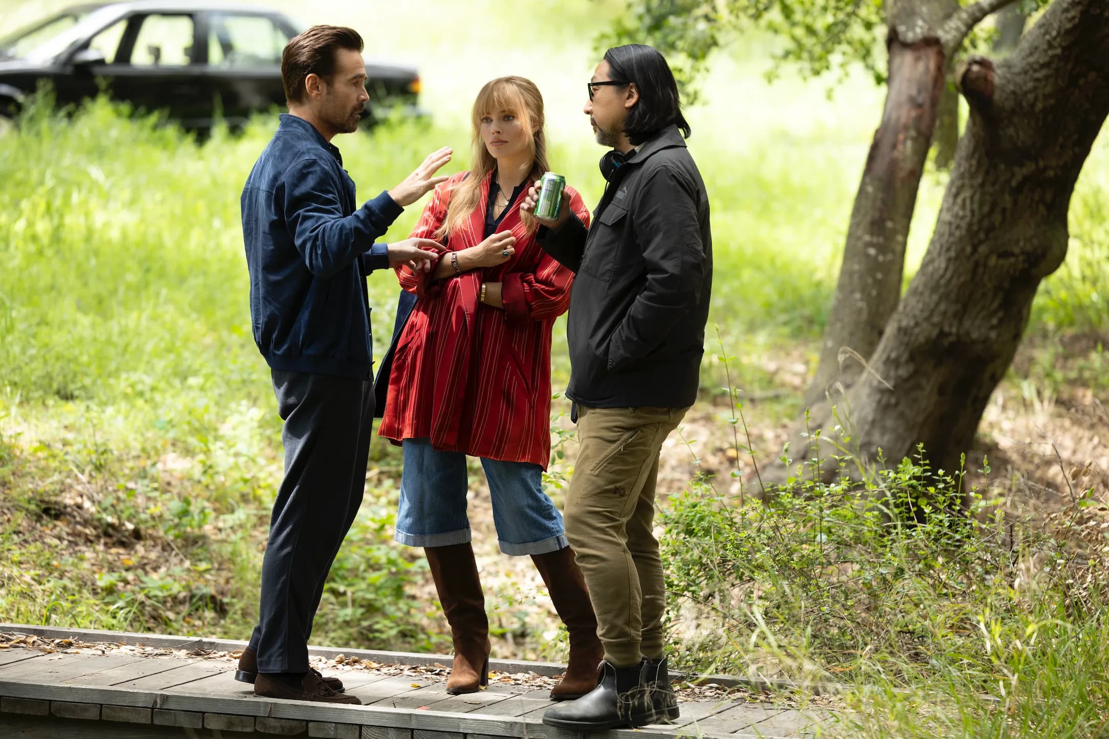 Colin Farrell, Margot Robbie, and director Kogonada stand outside talking on the set of "A Big Bold Beautiful Journey."