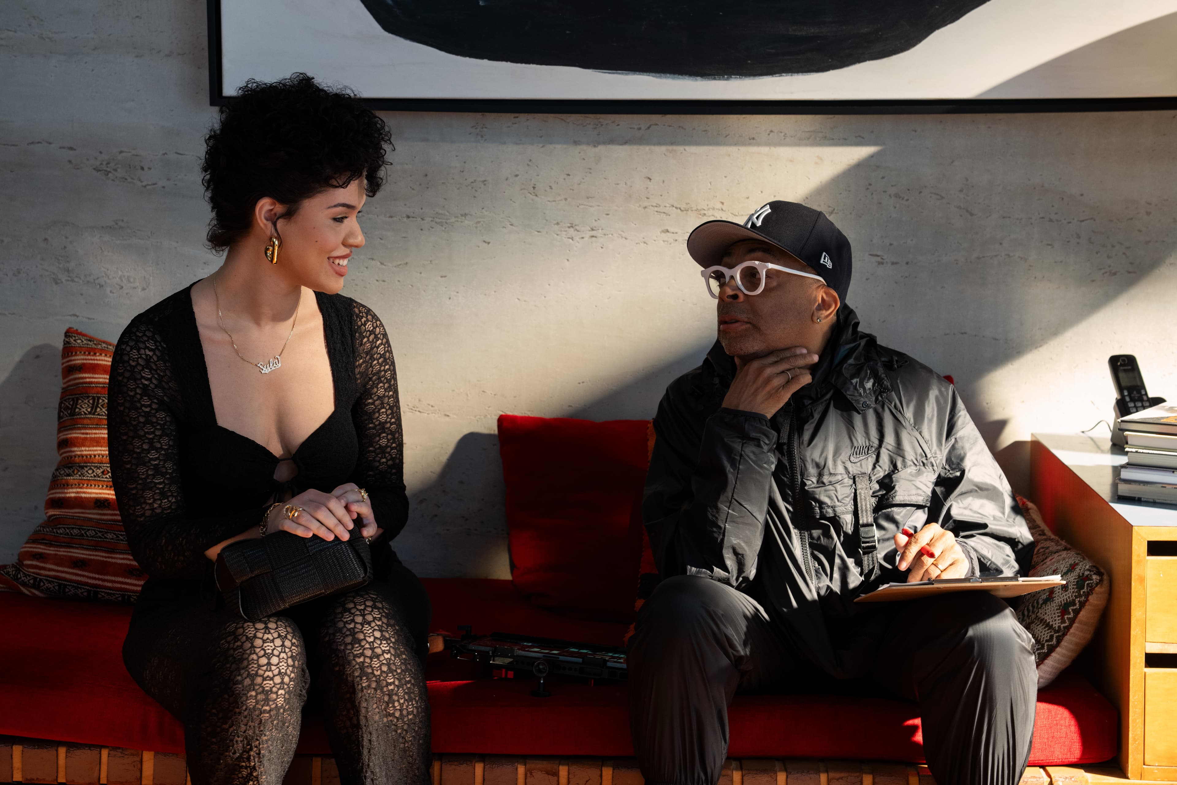 Actress Aiyana-Lee and director Spike Lee, each wearing black, sit on a couch on set of the film "Highest 2 Lowest."
