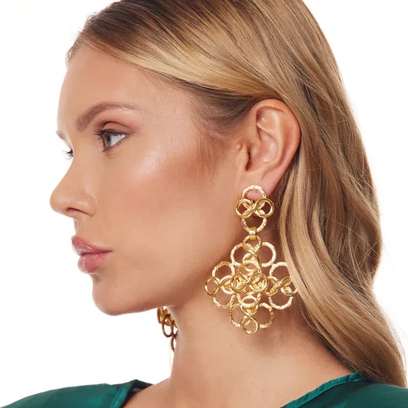 A blonde model wears gold Kenneth Jay Lane Fancy Swirl Clip Earrings