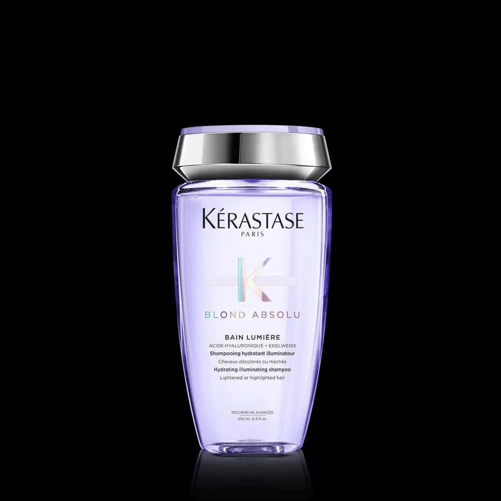 A see-through lilac-colored bottle of Kerastase shampoo against a gray background
